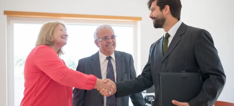a older couple dressed professionally shaking hands with a real estate agent