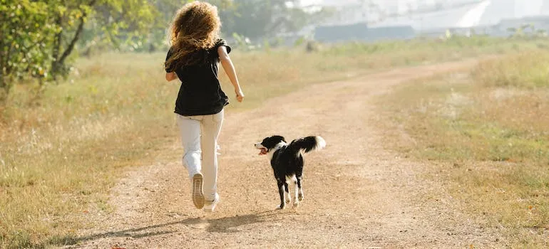 A woman and the dog running in the park representing pet friendly places and services in Columbia MD