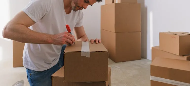 A person labeling a moving box