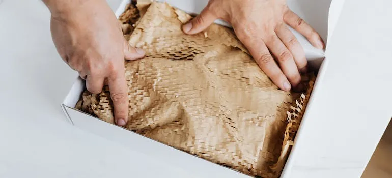 A person using packing paper to pack toys for moving to Bethesda