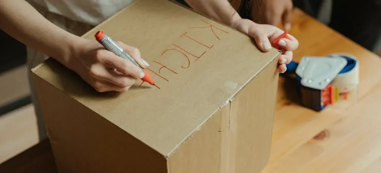 A person labeling a moving box