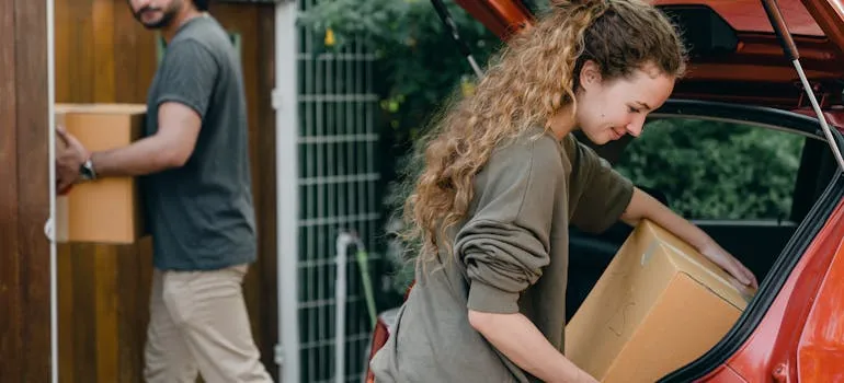 A couple unloading moving boxes from the car