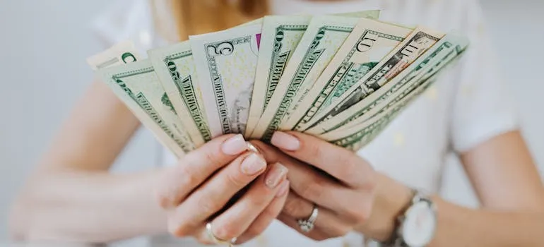 A person holding dollar bills thinking about reasons people relocate from Maryland to Virginia