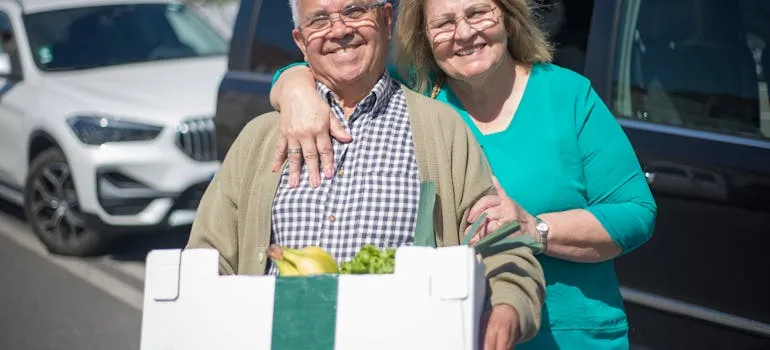 A couple holding a box of groceries 