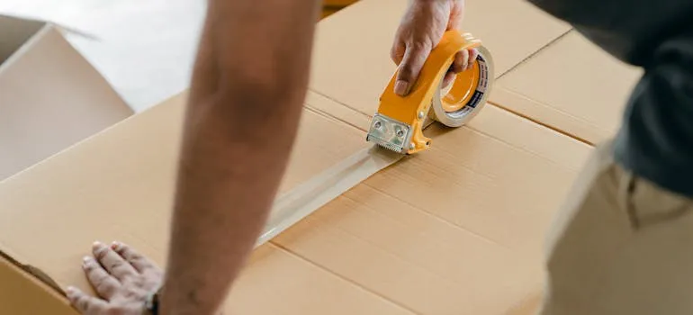 A man sealing a moving box