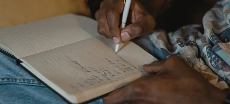 A person writing a checklist for moving from DC to Los Angeles