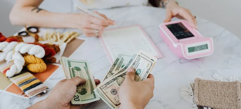 Two people counting dollar bills and talking about why DC area movers are essential for relocating