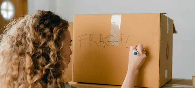 A woman labeling a moving box
