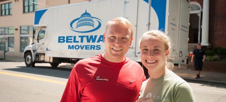 a couple  standing next to the Beltway moving van waiting for commercial movers in Maryland