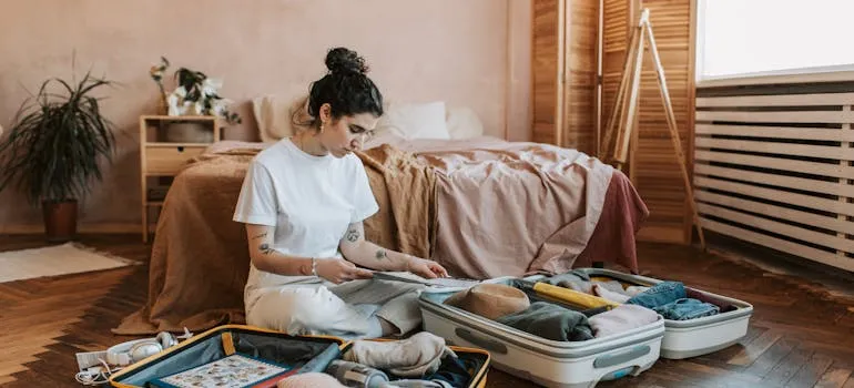 A woman using a room-by-room packing checklist to pack belongings