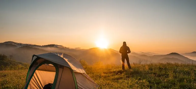 A person standing next to the camping tent