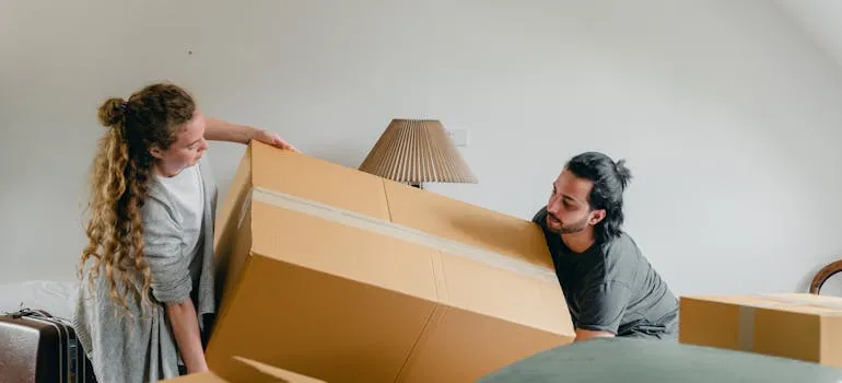 A couple carrying a moving box