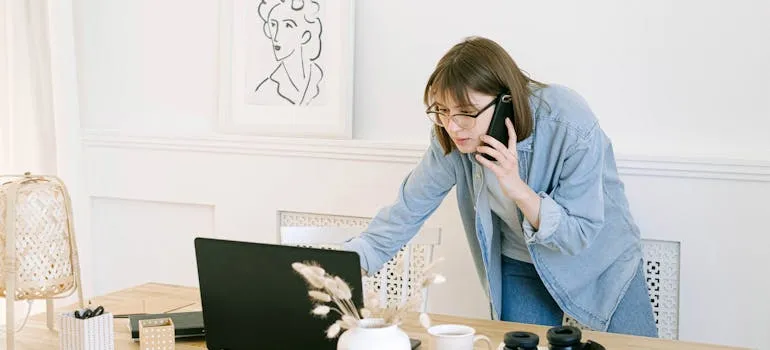 A woman in front of the laptop talking on the phone about how long distance movers simplify your move