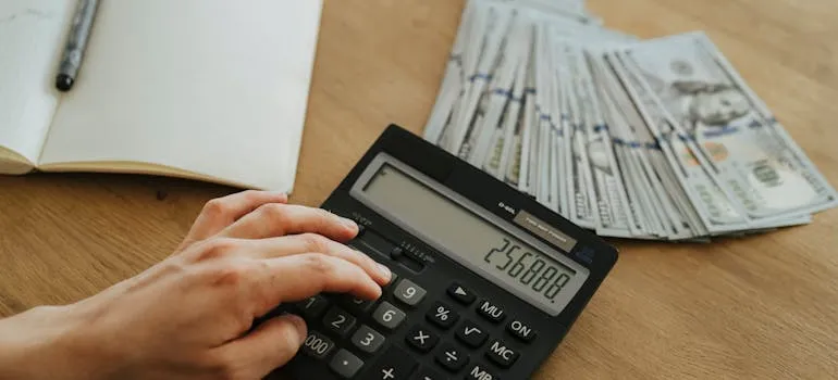 A person using calculator to budget for a specialty relocation services in Northern Virginia