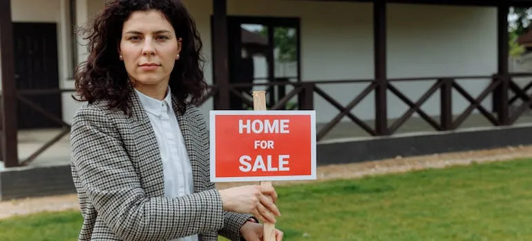 A person standing next to the home for sale sign