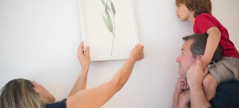 A family putting a picture on the wall