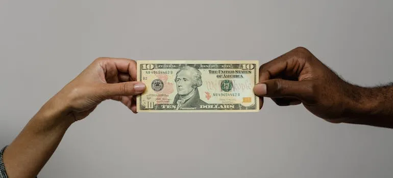 Two hands holding 10 dollars bill
