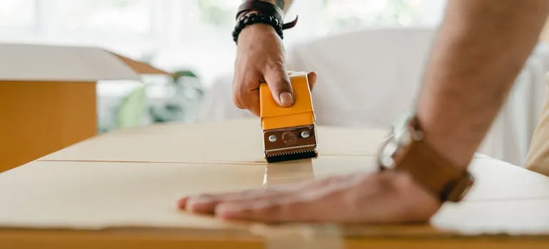 A person sealing a moving box 