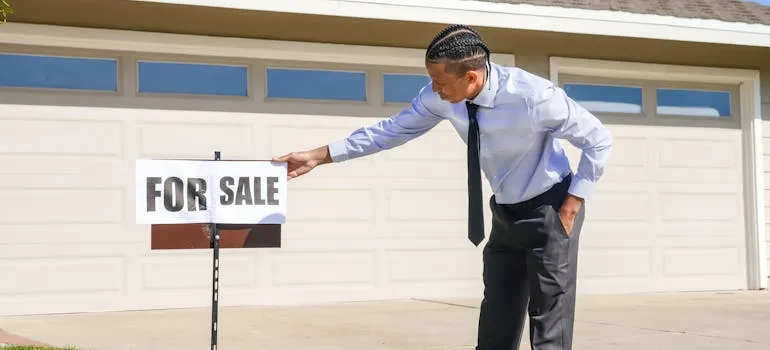 A man standing next to the for sale sign
