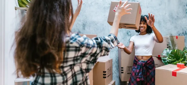 Two women throwing moving box