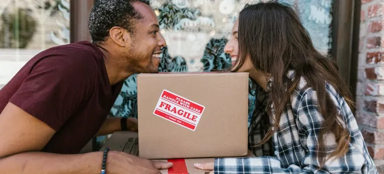 Two people holding moving box 