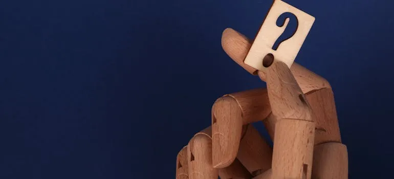 Wooden hand holding a question mark