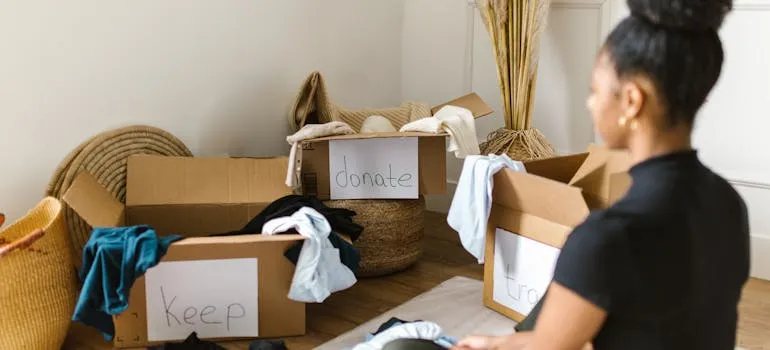 A woman using moving boxes to downsize your home when moving from DC to LA