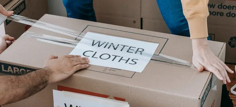 A person sealing a moving box