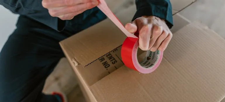 A man sealing a moving box