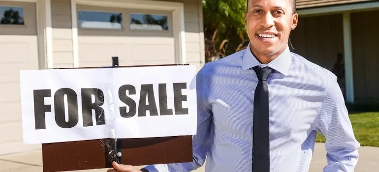 A person holding for sale sign 