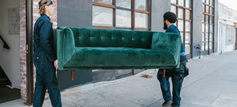 Two movers carrying sofa and talking about how weather in the DMV affects your move