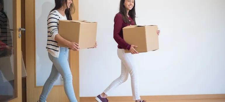 Two girls carrying boxes