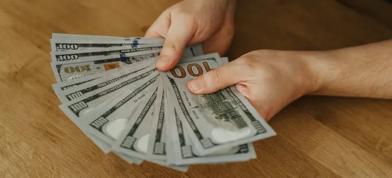 A person holding dollar bills and thinking about pros and cons of leaving DC for Austin