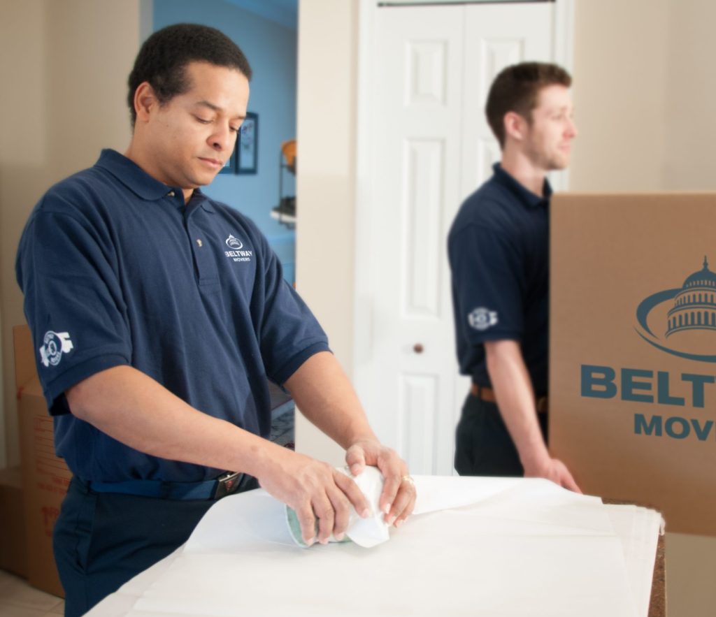 Beltway mover laying out packing paper while a second crew member carries a labeled Beltway carton.