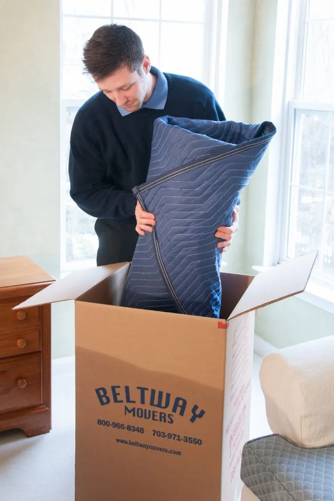 A person packing a blanket in a box.