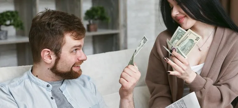 A couple holding dollar bills and talking about why Maryland residents are moving to Delaware